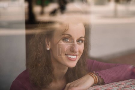 Mujer reflexiva mirando afuera desde una ventana de café