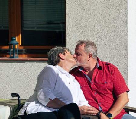 Téléchargez les photos : Moment romantique que le couple aîné échanger un baiser tendre en dehors de leur maison - en image libre de droit