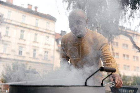 Senior Man in Yellow Sweater Smiling Near Cooking Pot on Urban Street