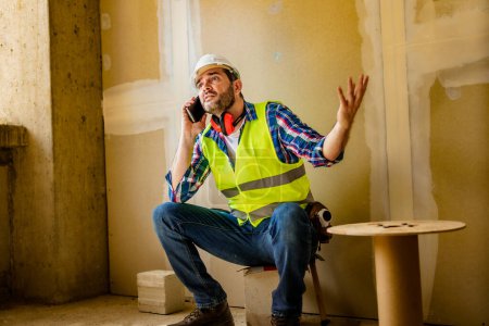 Constructor o contratista usando un teléfono móvil en el sitio de construcción.