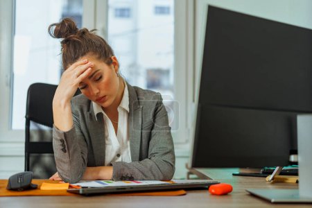 Téléchargez les photos : Finance executive is tired and burned out, she's worried about her companies finance she's holding her head as she tries to think of a plan - en image libre de droit