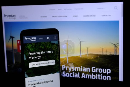 Foto de En primer plano, el sitio web del spa Prysmian Group se muestra en un teléfono inteligente y en segundo plano una página del sitio web de la empresa que cotiza en la Bolsa de Milán. - Imagen libre de derechos