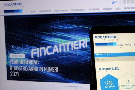 Foto de En primer plano, el logotipo de Fincantieri Spa, una empresa cotizada en la Bolsa de Milán. En el fondo, la página principal de la página web de Fincantieri. - Imagen libre de derechos