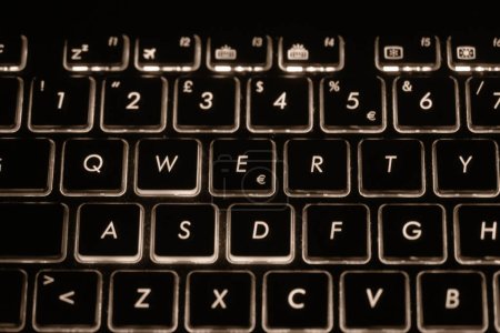 Detail der hinterleuchteten Tastatur eines ASUS-Laptops mit Sepia-Effekt.