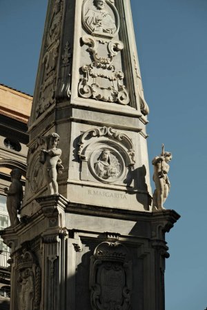 Foto de Detail of the Obelisk of San Domenico located in the center of Piazza San Domenico Maggiore in Naples, Italy. In the center we see the blessed Margarita depicted. - Imagen libre de derechos