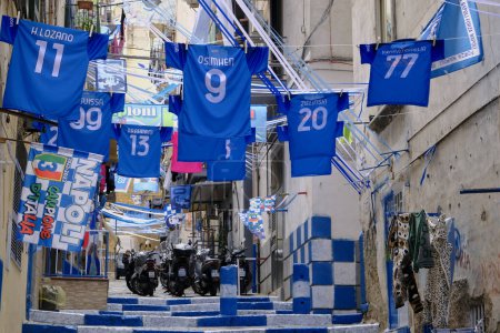 Foto de Camisas oficiales de SSC Napoli exhibidas en un histórico callejón de Nápoles, para celebrar el tercer campeonato de Nápoles. Napoli no había ganado un campeonato de fútbol desde la era de Maradona. - Imagen libre de derechos