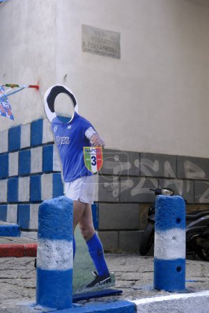 Foto de La silueta tótem de Diego Armando Maradona sosteniendo el tercer scudetto en la historia del fútbol napoleónico en una mano. - Imagen libre de derechos