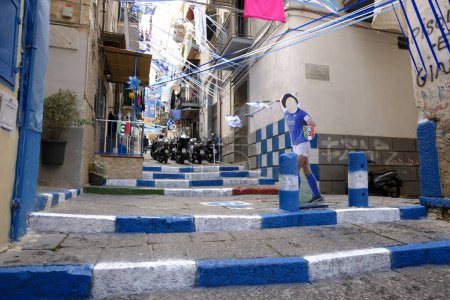 Photo for We are in Vico Rosario in Portamedina in the Montecalvario district in Naples. The steps of the alley have been colored white and blue and a life-size silhouette of Diego Armando Maradona is placed in the center as he awaits Napoli's third scudetto. - Royalty Free Image