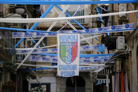 Foto de Bandera vertical con el tercer campeonato Napoli Calcio en el centro y la inscripción 'Napoli Champion of Italy 2022 /' 23. Alrededor de festones blancos y azules. Estamos en vico Caricatoio en el área de Vico Cariati en Nápoles. - Imagen libre de derechos