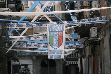 Foto de Bandera vertical con el tercer campeonato Napoli Calcio en el centro y la inscripción 'Napoli Champion of Italy 2022 /' 23. Alrededor de festones blancos y azules. Simulación de película Fujifilm Nostalgia Neg. - Imagen libre de derechos