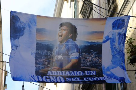 Foto de Banner con la imagen de Diego Armando Maradona exultante en el centro con la camisa Napoli y a los lados con la camisa Argentina. Bajo la inscripción: "Tenemos un sueño en nuestro corazón". Ganar el Scudetto 2022 - 2023. - Imagen libre de derechos