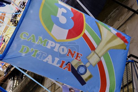 Foto de Bandera de Nápoles Campeón de Italia con el tercer escudo Napoli SSC suspendido en los callejones de la ciudad napolitana. - Imagen libre de derechos
