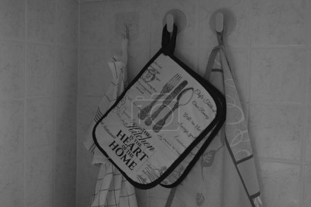 Potholders hung on the wall in the kitchen between tea towels to dry pots and dishes. The photograph of the pot holders was taken in black and white.