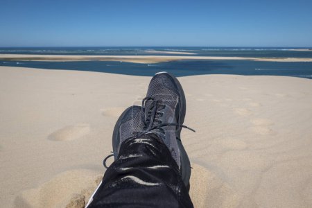 Téléchargez les photos : Touriste assis jambes croisées reposant dans les Dunes de Pilat avec la plage en arrière-plan en France - en image libre de droit