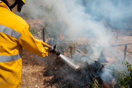 Téléchargez les photos : Pompier avec le tuyau éteignant un feu - en image libre de droit