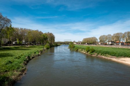 Fluss Adour, umgeben von grünem Gras und einigen Bäumen in Dax im Baskenland, Frankreich