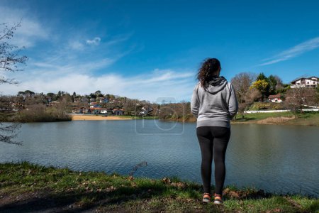 Foto de Mujer turista en el lago Alain Cami en Saint Pee sur Nivelle disfrutando del paisaje que la rodea mientras descansa - Imagen libre de derechos