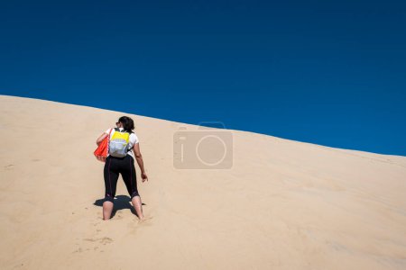 Téléchargez les photos : Femme touristique en grand effort escalade les Dunes du Pilat au Pays Basque, France - en image libre de droit