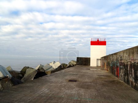 Photo for Dike on the Digue beach in Boucau in the Basque Country in France, with a lighthouse in front on a cloudy day - Royalty Free Image