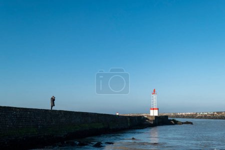 Photo for Dike on the beach of the Digue in Boucau in France, with a tourist photographer taking pictures - Royalty Free Image