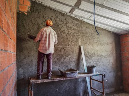 Foto de Mason worker putting cement on the wall to finish the wall with plaster - Imagen libre de derechos