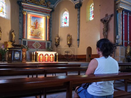 Téléchargez les photos : Femme croyante assise sur un banc en bois priant devant l'autel - en image libre de droit