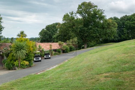 Téléchargez les photos : Chariots de golf garés sur le bord de la route pour la pratique du sport de golf par une journée très nuageuse - en image libre de droit
