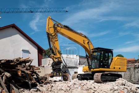 Téléchargez les photos : Pelle rétrocaveuse démolir une vieille maison pour une construction ultérieure sur le site - en image libre de droit