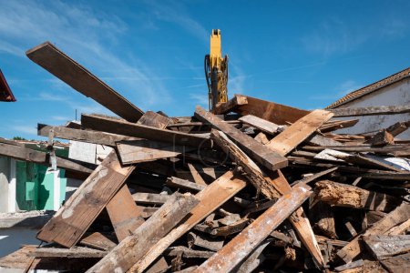 Foto de Montón de madera después de la destrucción de una casa por una retroexcavadora en un día soleado - Imagen libre de derechos