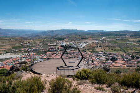 Photo for Round viewpoint with metal structure and wooden floor and a hexagonal swing next to the little chapels in Vila Flor and with the town in the background - Royalty Free Image