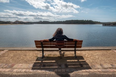 Sérénité au bord de la rivière : Une touriste assise sur un banc en bois tout en admirant les paysages idylliques du Vieux Boucau Les Bains au Pays Basque, France