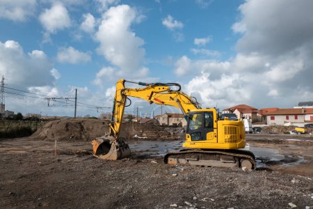 Photo for Rotary backhoe loader on site preparing land leveling for residential construction - Royalty Free Image