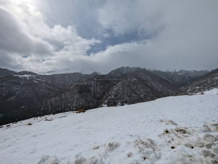 Panorama hivernal : Vue panoramique sur les montagnes avec beaucoup de neige à l'horizon par une froide journée d'hiver avec un ciel très nuageux