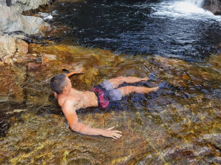 Téléchargez les photos : Exploration aquatique : Aventures d'un jeune homme nageant dans un ruisseau naturel - en image libre de droit