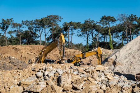 Backhoe loaders operating in a quarry, moving and loading rocks for crushing