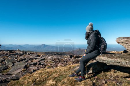 Touristin auf dem Gipfel des Berges sitzt auf einem Felsen und genießt die Landschaft während sie sich ausruht