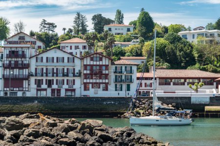 Foto de Barco que pasa por el río con parte de la ciudad de Saint Jean de Luz al fondo con casas típicas del País Vasco en Francia - Imagen libre de derechos