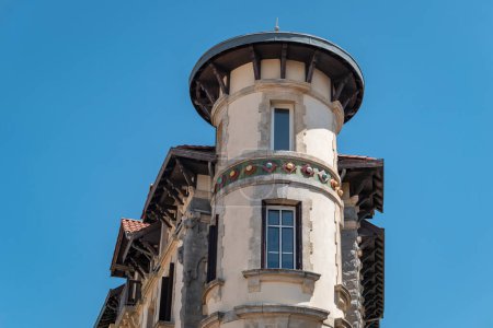 Detalles de una casa antigua con una fachada delantera en forma de torre redondeada contra un cielo azul