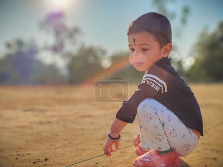 Photo for Cute little baby boy playing with rope  in a park and smiling. Child crawling in a public park and looking up with happy face. View from bottom. Copy space - Royalty Free Image