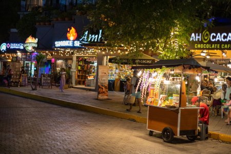 Foto de PLAYA DEL CARMEN, México - Feb 2023: En el encantador ambiente de una noche, se desarrolla una vibrante escena en la Av. Constituyentes como una variedad de puestos y tiendas iluminan las calles. Foto de alta calidad - Imagen libre de derechos