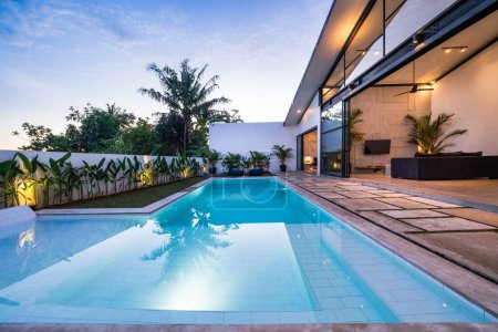 Photo for Tropical villa view with garden, swimming pool and open living room at sunset. - Royalty Free Image