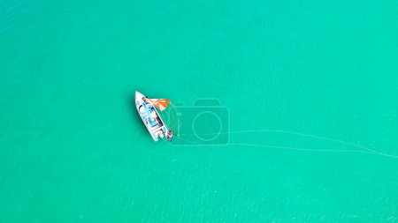 Photo for View from above of clear sea water with staff and tourists heading to boat after finished parasailing. - Royalty Free Image