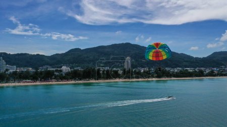 Photo for Tourist is enjoying a parasailing ride at Patong beach in Phuket of Thailand. Water sport activity. Thailand extreme Sports. - Royalty Free Image