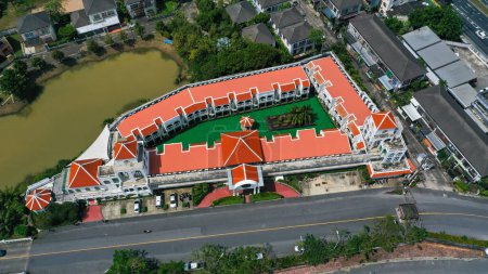 Téléchargez les photos : Vue aérienne par drone de l'hôtel avec la couleur rouge du toit et la piscine à l'intérieur de l'hôtel. Hôtel à Ko Kaeo, Phuket, Thaïlande. - en image libre de droit