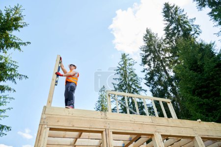 Photo for Side view of professional builder standing high, holding, putting, measuring wooden gilder. Male worker, engineer building, constructing, wearing helmet. Concept of building, - Royalty Free Image