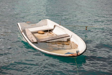 Téléchargez les photos : Un vieux bateau de pêche blanc qui fuit immergé dans l'eau bleue. Pêche maritime. - en image libre de droit