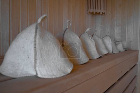 Téléchargez les photos : Gros plan Des chapeaux de laine pour les bains et les saunas se trouvent sur un banc en bois dans le hammam. Chapeaux de sauna. - en image libre de droit