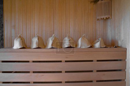 Photo for Close-up woolen hats for baths and saunas lie on a wooden bench in the steam room. Sauna hats. - Royalty Free Image