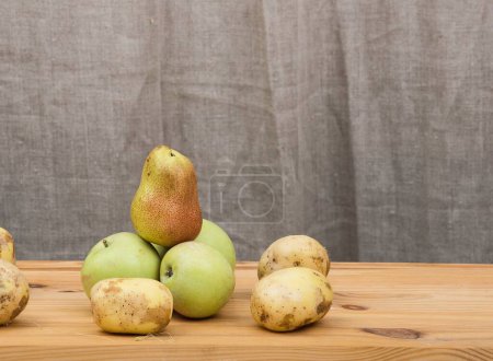 Photo for Juicy yellow autumn pears and ripe green apples lie on a wooden rustic table in a farmhouse.High quality photo. - Royalty Free Image
