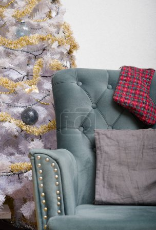 Festliche Zimmerdekoration für den Familienurlaub im Winter. Ein gemütlicher Sessel steht neben einem weihnachtlich geschmückten Weihnachtsbaum.